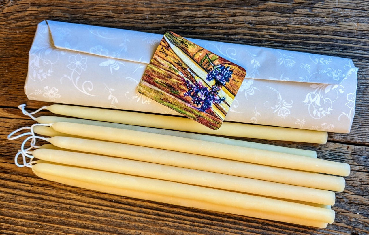 yellow beeswax tiny taper candles lying next to a bundle of wrapped tapers on a table
