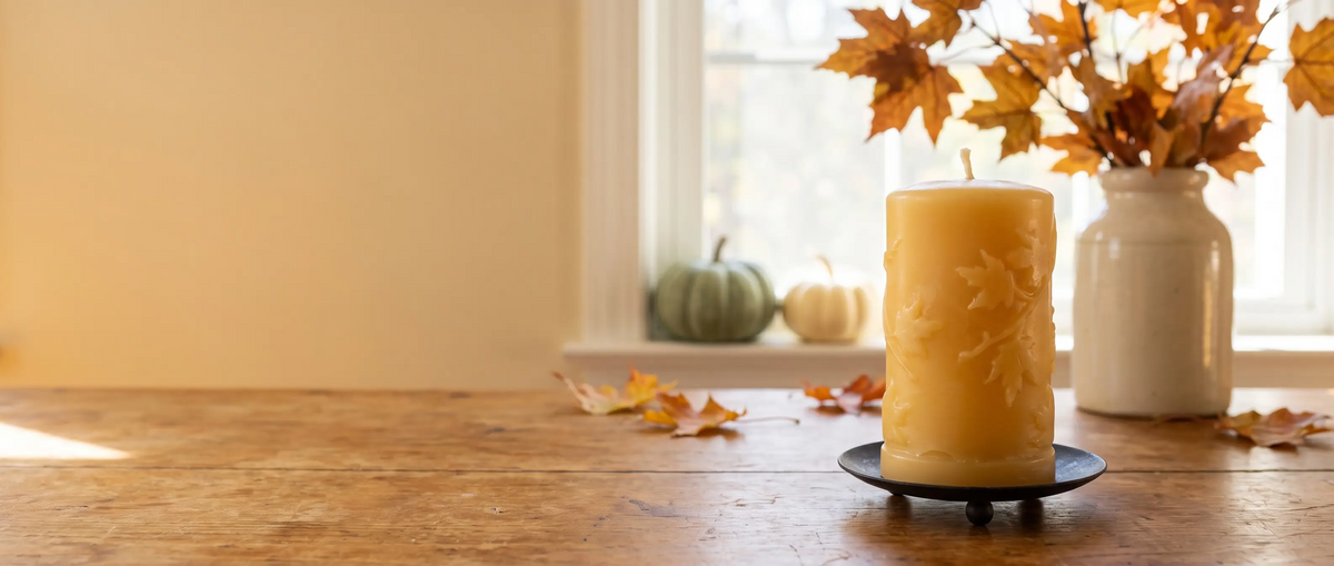 Lit beeswax pillar candle glowing on a windowsill at dusk