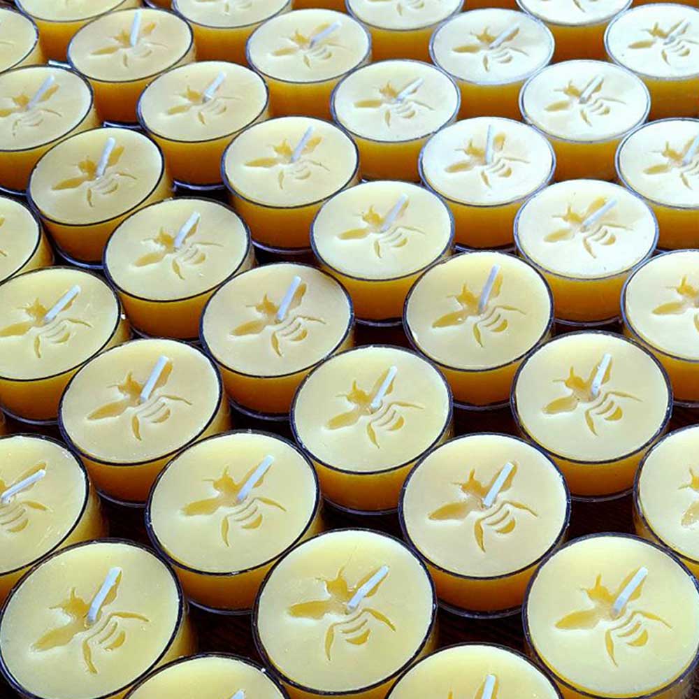 Beeswax tealights arranged in a box and  seen from above to show the bee imprint