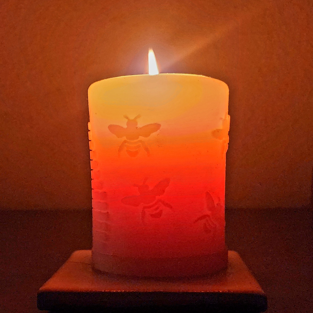 'Busy Bees' beeswax pillar candle, lit