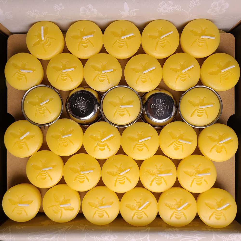 Moon Drop refillable beeswax tea light, lit in its stainless steel cup