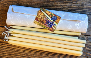 yellow beeswax tiny taper candles lying next to a bundle of wrapped tapers on a table