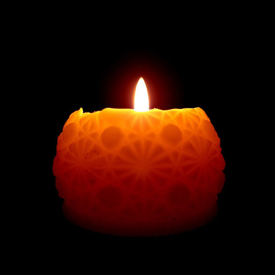round beeswax candle with intricate pattern