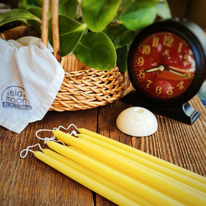 yellow tiny beeswax tapers lying on a table with a white ceramic taper holder next to them