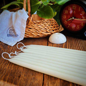 ivory colored tiny tapers lying on a table with a white ceramic taper holder next to them